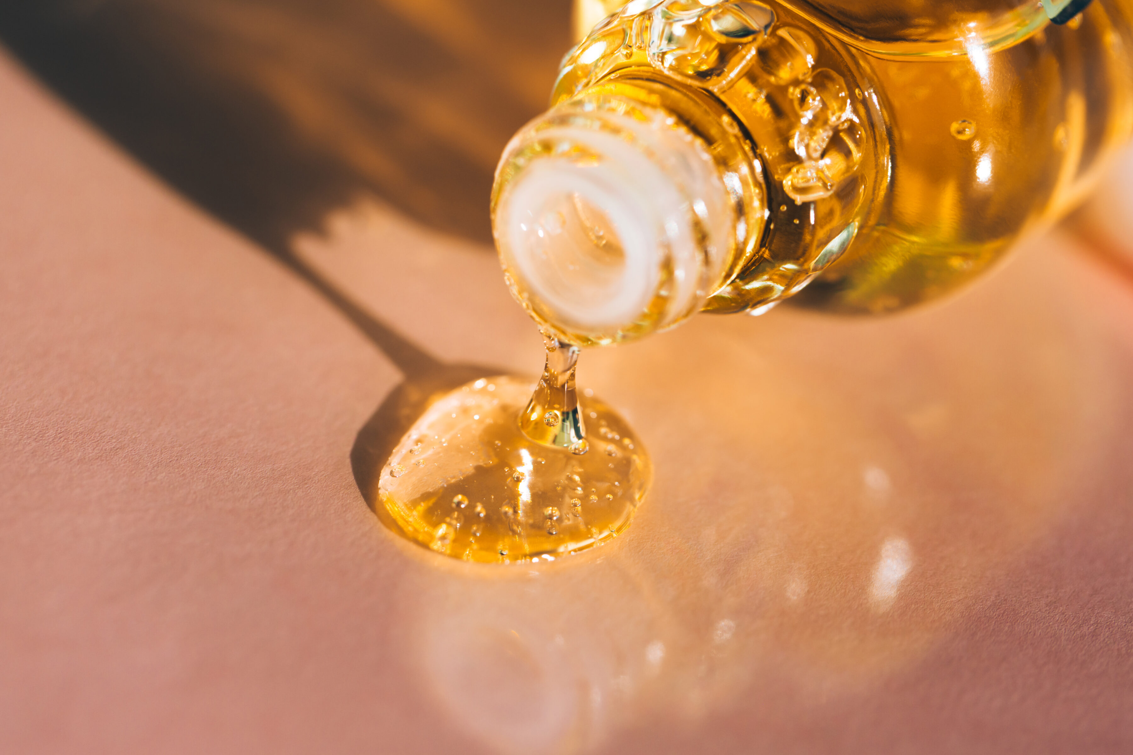 A bottle of hair oil spills on a glossy surface