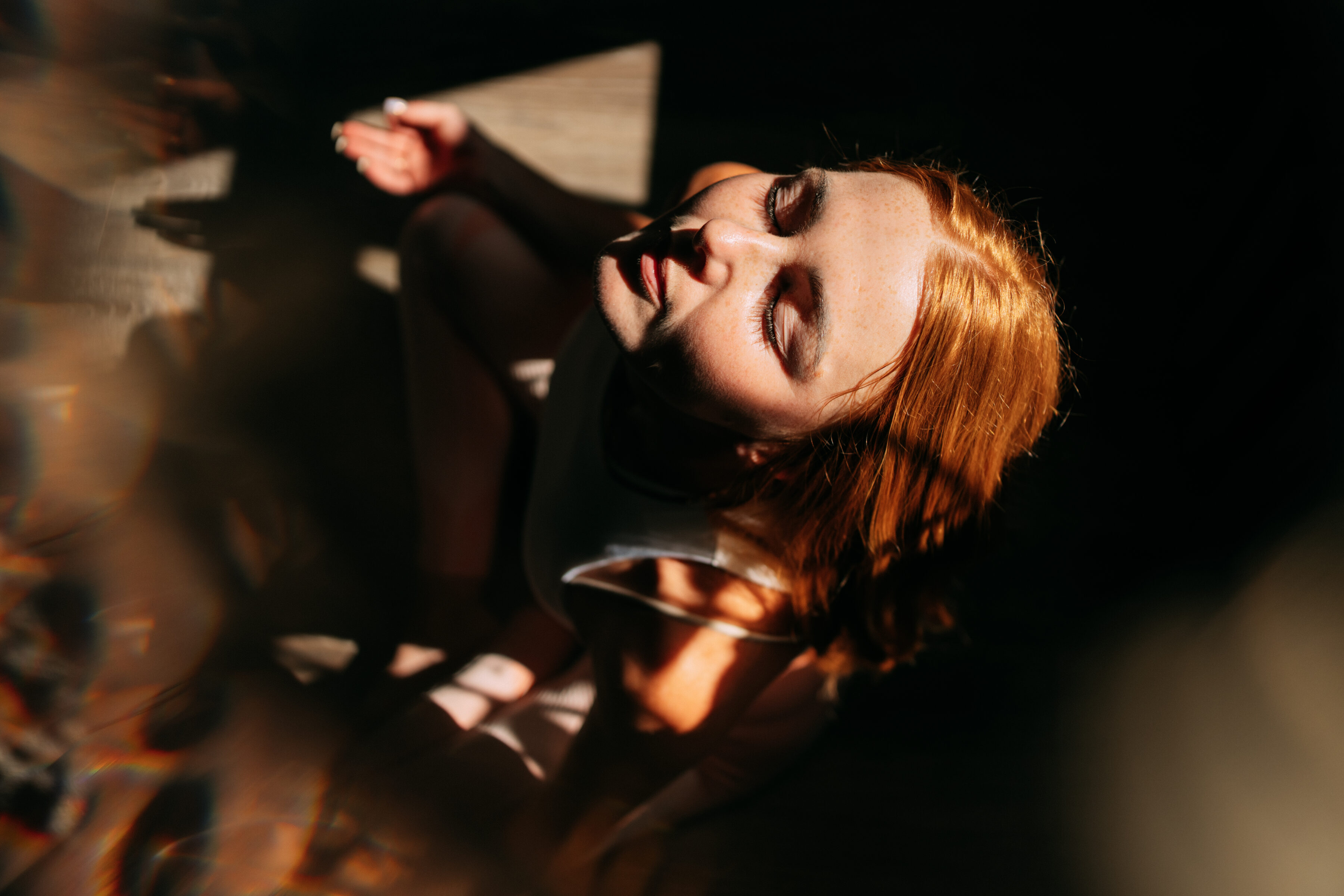 Redhead woman meditating with closed eyes, enjoying the sunlight.