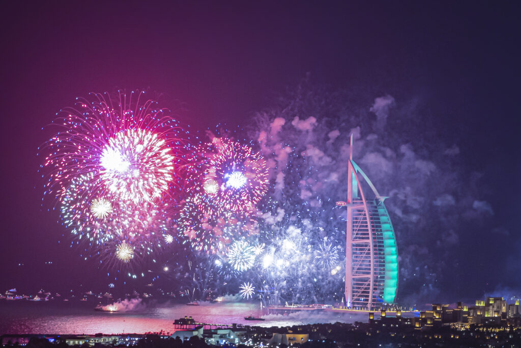 Fireworks display over Burj Al Arab in Dubai, celebrating New Year's Eve with vibrant colors and a festive atmosphere.