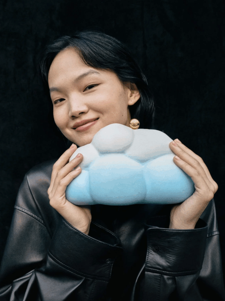 Model holding a whimsical blue and white cloud-shaped clutch bag, showcasing luxury fashion for Lunar New Year celebrations.