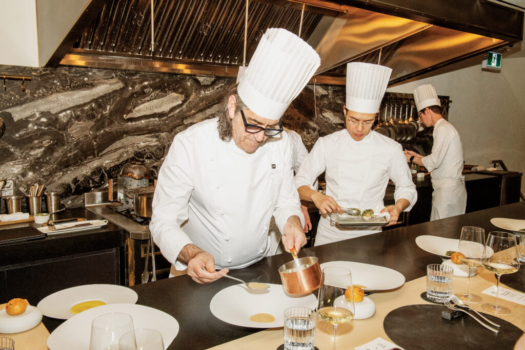 Chefs in a Michelin-starred kitchen preparing dishes, highlighting culinary excellence for the 3 magazine Ambassador Program launch event.
