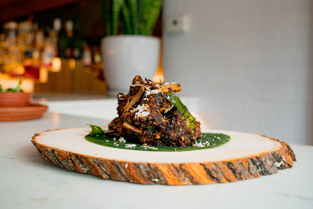 Plate of South Asian cuisine featuring a beautifully presented dish on a wooden slab, showcasing intricate flavors and textures, emphasizing fine dining aesthetics.